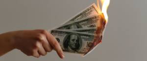 Une main qui tient des billets de dollars en feu