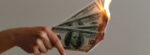 57% des Français pensent qu'il faut changer de modèle économique Une main qui tient des billets de dollars en feu