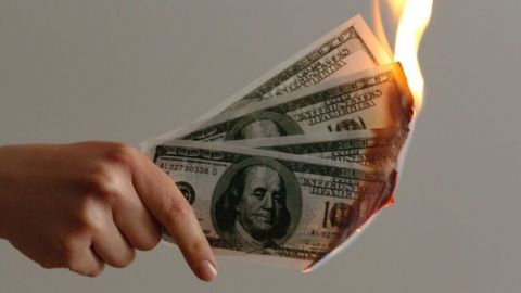 Une main qui tient des billets de dollars en feu