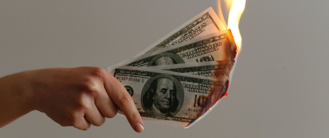 57% des Français pensent qu'il faut changer de modèle économique Une main qui tient des billets de dollars en feu