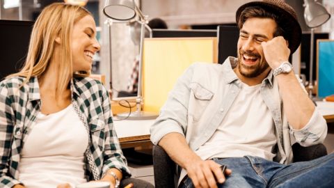 Un homme et une femme en train de rire au bureau