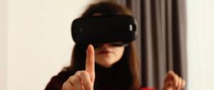 Femme portant un casque de réalité virtuelle essaye de toucher un objet