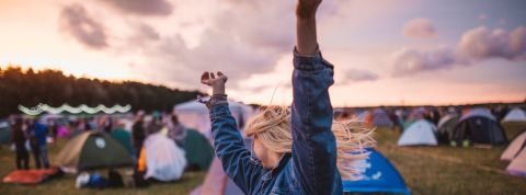 Cashless en festival : libérés des billets, mais pourquoi faire au juste ? Jeune femme danse et lève les bras pendant un festival de musique.