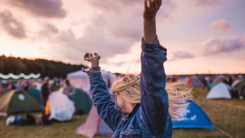Jeune femme danse et lève les bras pendant un festival de musique.