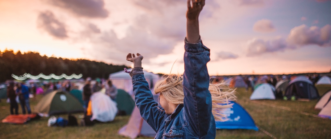 Cashless en festival : libérés des billets, mais pourquoi faire au juste ? Jeune femme danse et lève les bras pendant un festival de musique.