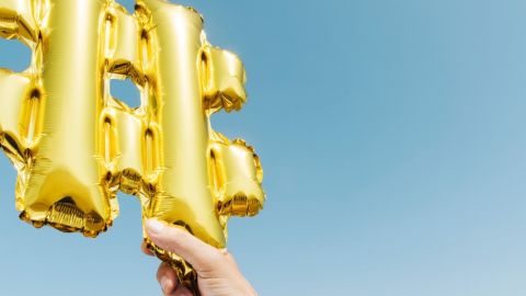 une main tient un ballon doré en forme de dièse