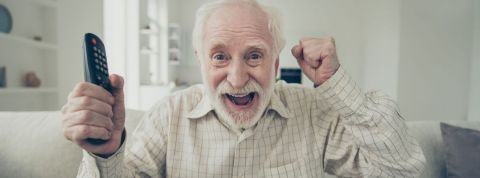 Découvrez les longévistes, les transhumanistes convaincus que la mort est évitable Un homme âgé sourit et tient une télécommande sur son canapé