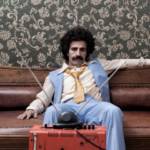 Un homme déprimé sur son canapé, dans une décoration très seventies.