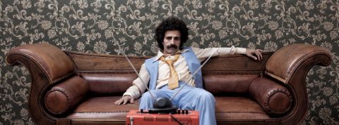 Comment attirer les talents quand on est une marque jugée ringarde ou austère ? Un homme déprimé sur son canapé, dans une décoration très seventies.