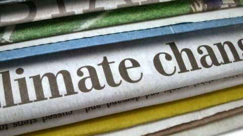 Des journeaux papiers avec le titre changement climatique dessus.