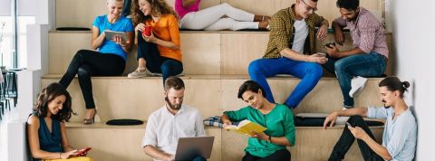Les réseaux à la pause café, c'est une mauvaise idée. un groupe de gens assis sur une estrade de bois en train de regarder leur portable.