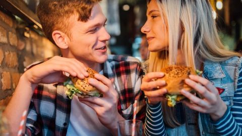 Un homme et un femme qui mangent un burger en se regardant