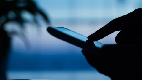 Main utilisant un smartphone dans l'ombre