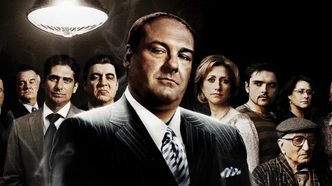 un homme habillé en mafieux avec ses acolytes en arrière plan.