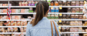 Une femme de dos regardant un rayon de supermarché