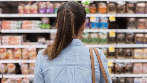 Une femme de dos regardant un rayon de supermarché