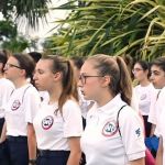 une jeune influenceur au garde à vous dans la jungle avec d'autres jeunes.