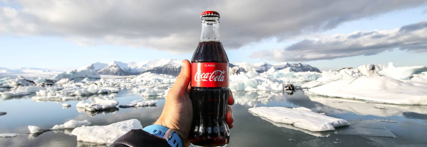 « Parlons-en ensemble ! » Coca-Cola France reçoit des internautes pour répondre aux critiques et démêler le vrai du faux Bouteille de coca cola dans la main d'un homme devant la banquise