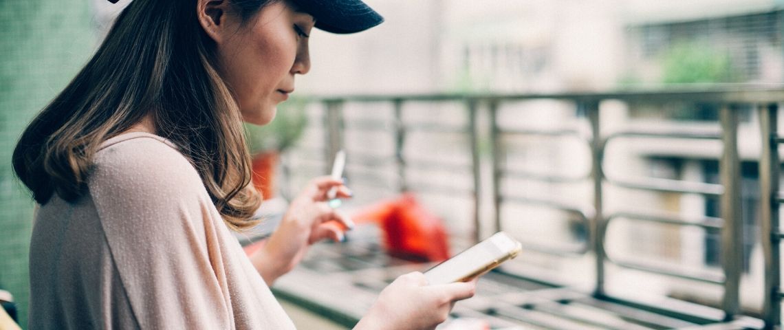 Social-ads-facebook-linkedin Une femme fume une cigarette en consultant son téléphone