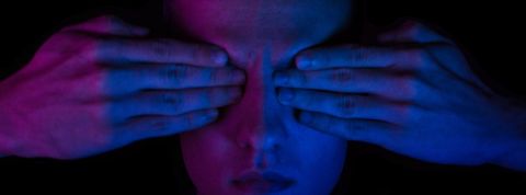 les aveugles sur les réseaux : les grands oubliés oubliés du numérique ? Une homme dans la pénombre avec ses deux mains sur les yeux. Bigup à tous les DV.