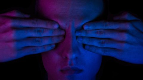 Une homme dans la pénombre avec ses deux mains sur les yeux. Bigup à tous les DV.