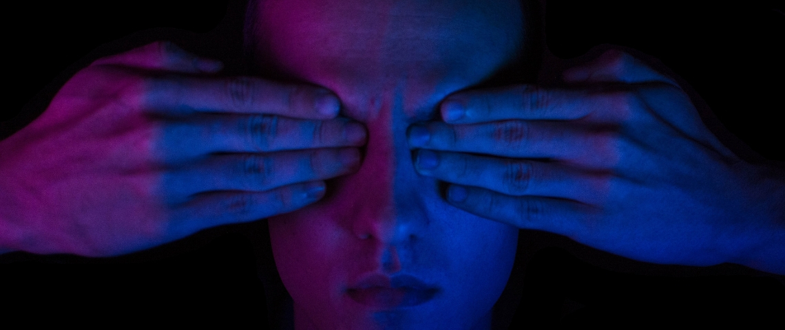les aveugles sur les réseaux : les grands oubliés oubliés du numérique ? Une homme dans la pénombre avec ses deux mains sur les yeux. Bigup à tous les DV.