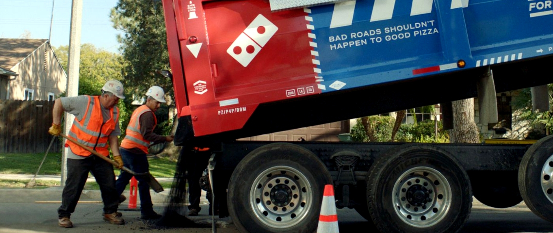 Redynamiser villes et collectivités locales, un job pour la pub ? camion dominos pizza reconstruisant la route