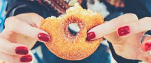 Les mains d'une femme qui tiennent un donut entamé