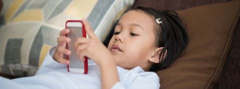 Le temps passé devant les écrans eszt moins important que la présence des parents une petite fille asiatique devant son portable