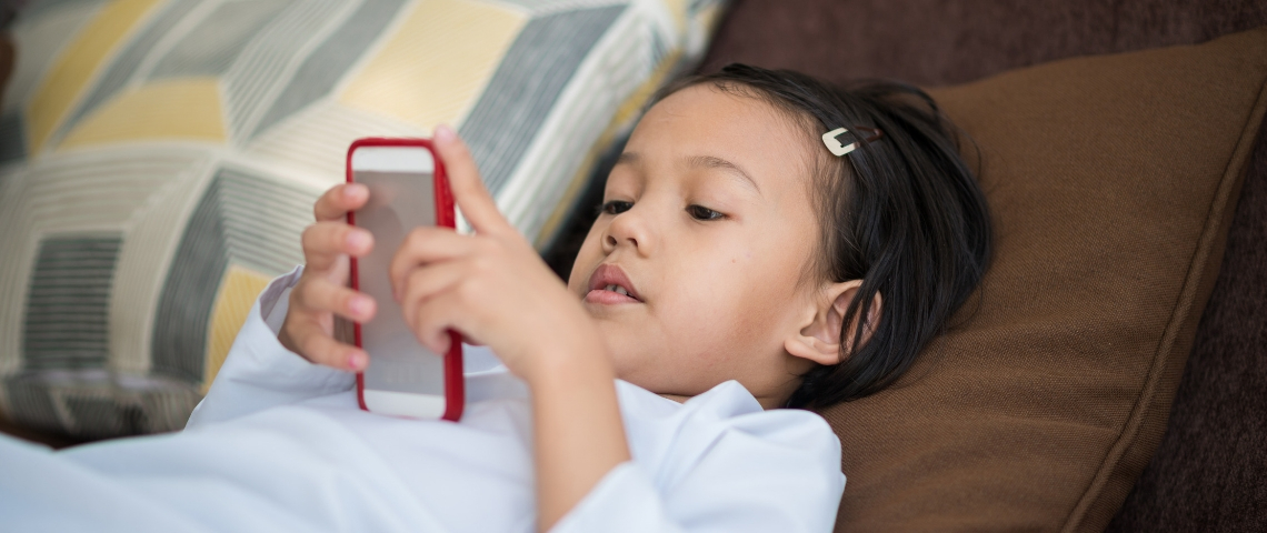 Le temps passé devant les écrans eszt moins important que la présence des parents une petite fille asiatique devant son portable