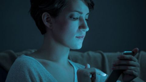 Une femme qui regarde son écran de téléphone dans le noir