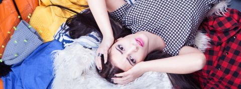 Arnaques, fripes et problèmes techniques... Vinted est-il victime de son succès ? Femmes stressée allongée sur une pile de vêtements