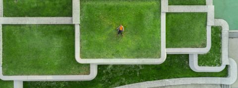 Comment réduire l'impact écologique de l'immobilier ? Un homme allongé sur le toit d'un immeuble recouvert de pelouse