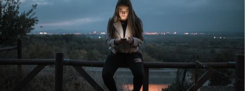 Les jeunes dévoilent ce qui se cache dans leur téléphone portable une jeune fille assise sur une barrière qui regarde son téléphone.