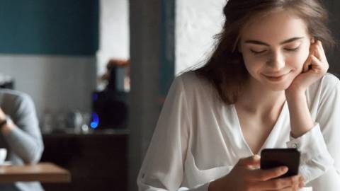 Une adolescente qui regarde son téléphone en souriant
