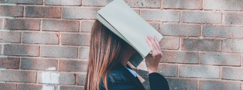 La reconnaissance faciale au lycée, ni légale ni nécessaire selon la Cnil jeune femme masquant son visage avec un cahier