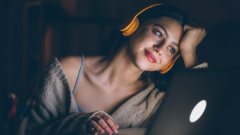 Une femme regarde une vidéo sur son ordinateur portable.