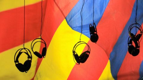 Des casques audio suspendu dans le vide avec un drat jaune rouge et bleu en arrière plan.