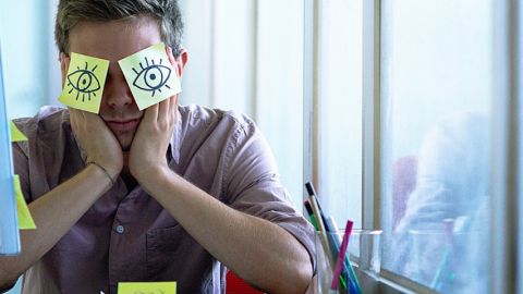 Un employé de bureau avec des post-it collés sur les yeux