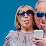 un couple de séniors tire la langue devant un smartphone