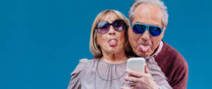 un couple de séniors tire la langue devant un smartphone