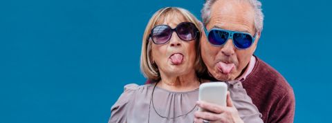 Papa et maman quand ils commentent ton fil facebook un couple de séniors tire la langue devant un smartphone