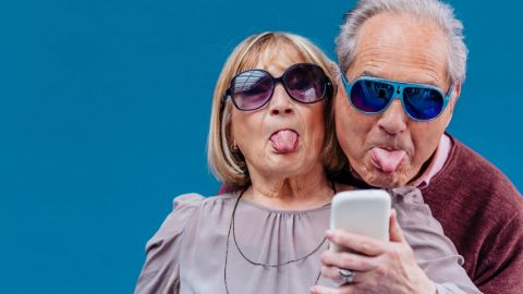 un couple de séniors tire la langue devant un smartphone