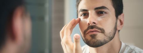 5 marques de beauté éco-responsables Un homme qui met de la crème sous ses yeux devant un mirroir