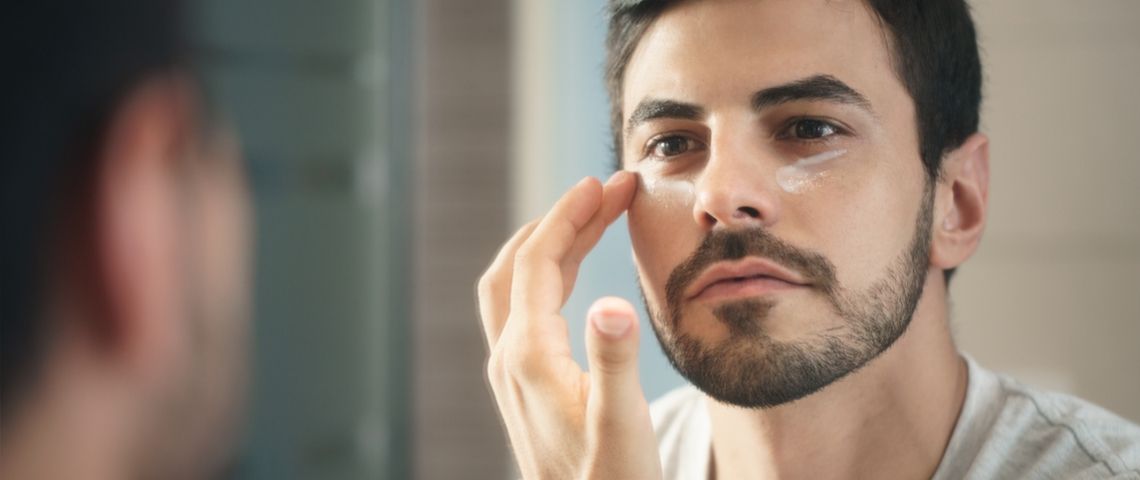 5 marques de beauté éco-responsables Un homme qui met de la crème sous ses yeux devant un mirroir