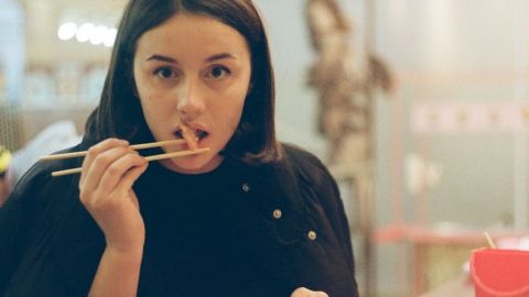 Une femme qui mange une crevette avec des baguettes