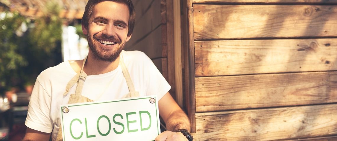 Ces entreprises qui boycottent le Black Friday (et qui y gagnent) Un jeune homme souriant tient une pancarte de boutique