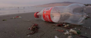 Une bouteille en plastique de Coca-Cola vide sur la plage