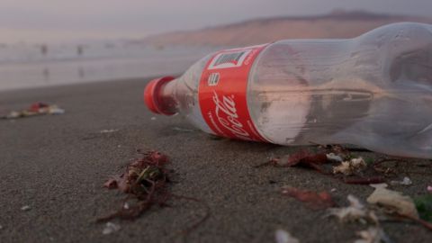 Une bouteille en plastique de Coca-Cola vide sur la plage