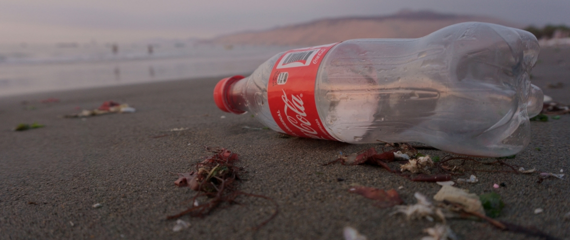 Qui sont les entreprises les plus polluantes ? Une bouteille en plastique de Coca-Cola vide sur la plage